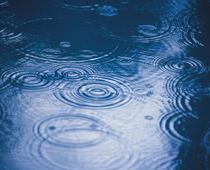 Sinnbild Regentropfenringe in Pfütze für die Botschaft des Regen-Geistes